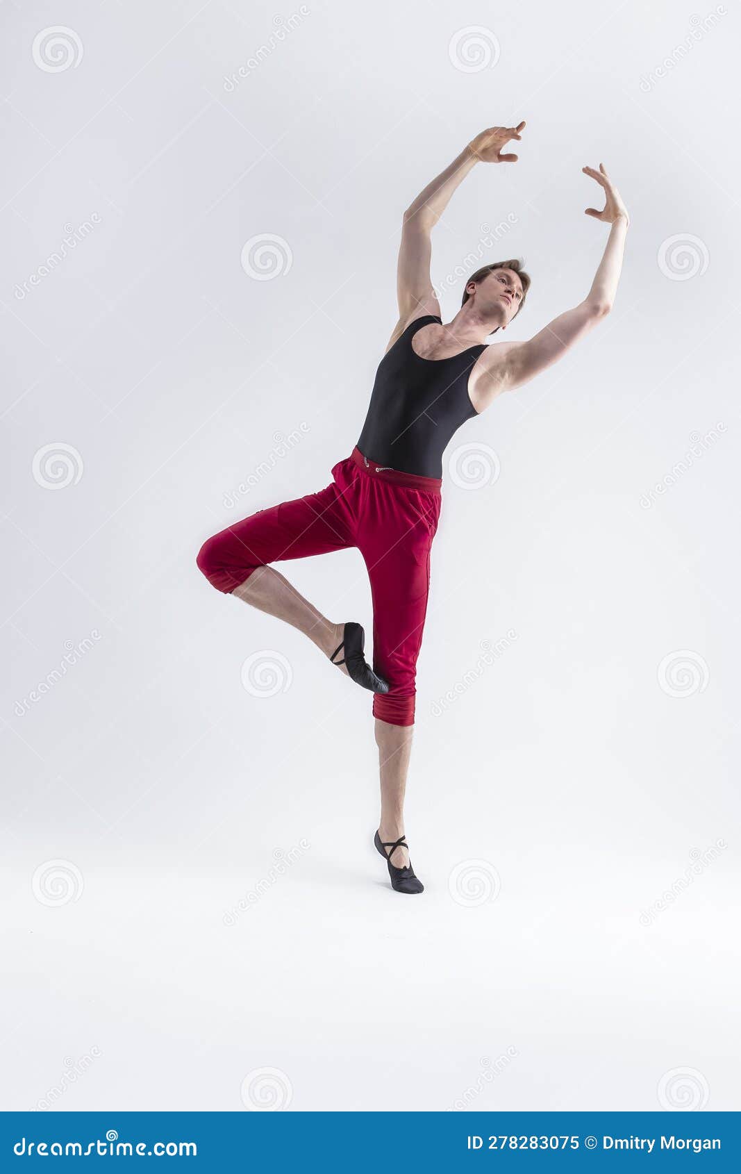 ballet ideas. modern ballet of flexible athletic man posing in red tights in ballanced dance pose with hands lifted in studio on