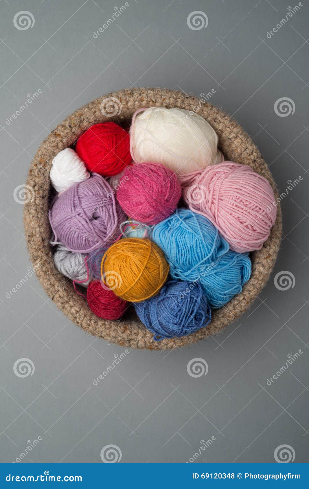 Balls of Colour Wool in Crocheted Bowl on Grey Background Stock Photo