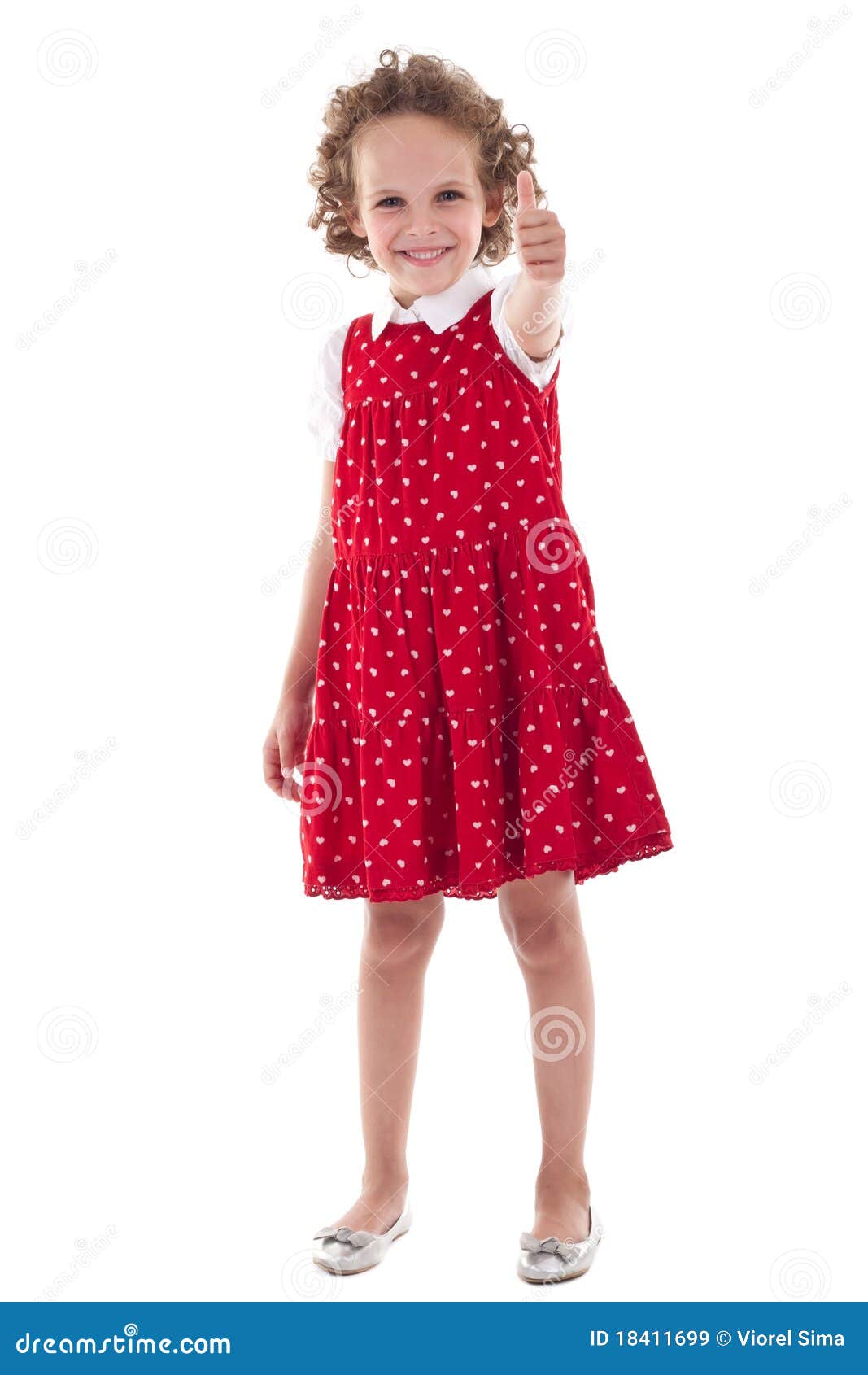 Bambina che gesturing i pollici in su. Bambina sveglia che porta vestito rosso, gesturing i pollici in su, isolato