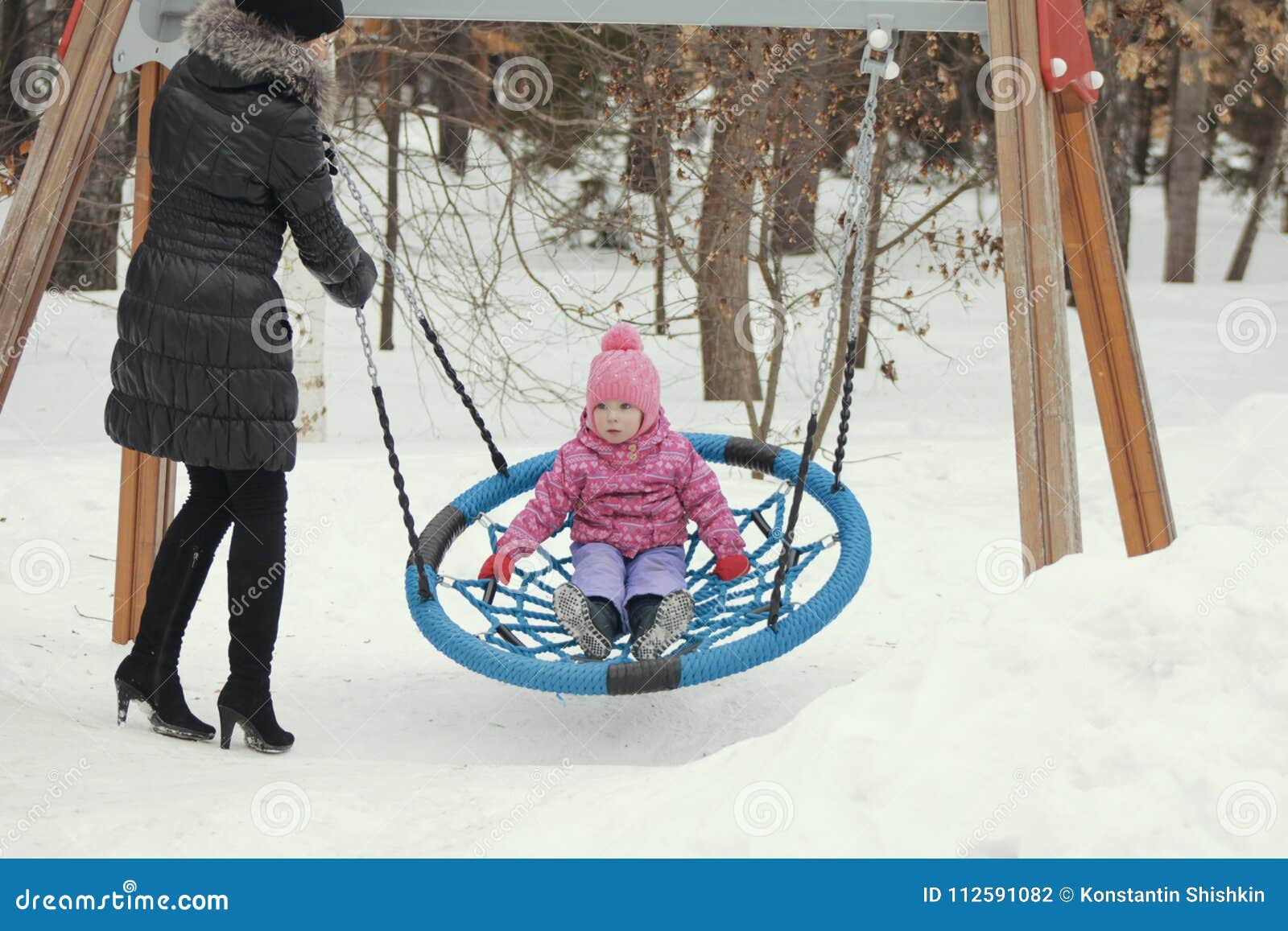 Bambina Sveglia Che Oscilla Su Un Oscillazione Sul Campo Da Giuoco Nell Inverno Fotografia Stock