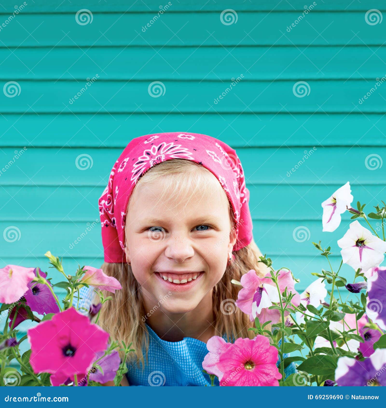 Bambina sveglia in giardino su fondo del recinto del turchese. Ritratto di una bambina sveglia in un giardino su un fondo del recinto del turchese