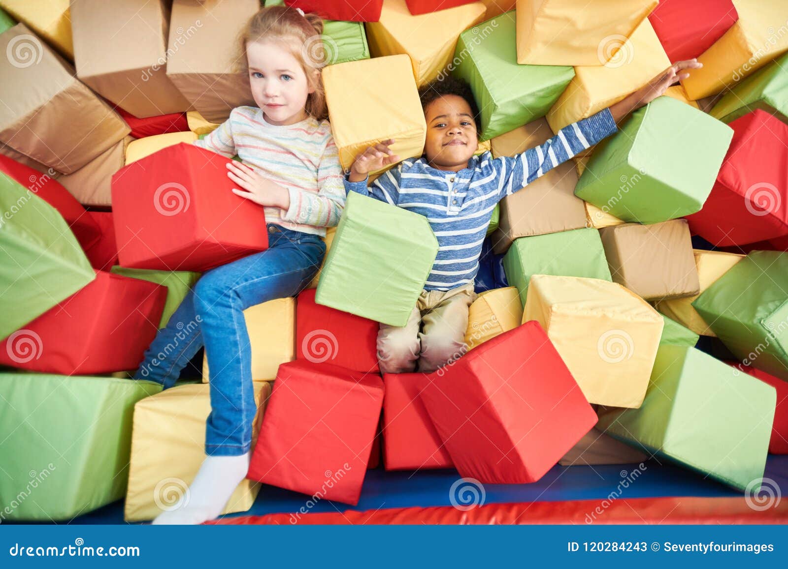 Bambini che giocano nel pozzo della schiuma. Variopinto sopra un ritratto di vista di due bambini felici che giocano nel pozzo della schiuma del centro del trampolino, spazio della copia