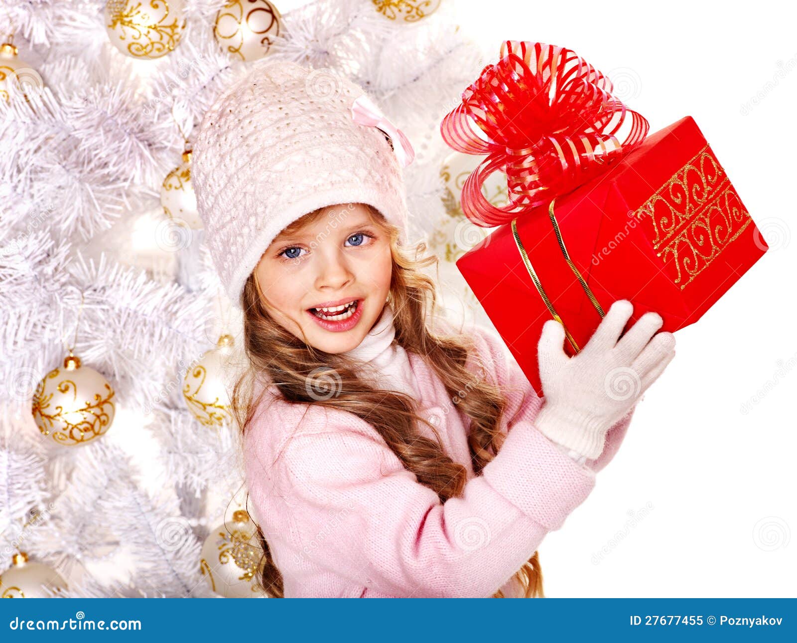 Bambino in cappello e guanti che tengono il contenitore di regalo rosso. Bambino in cappello e guanti che tengono il contenitore di regalo rosso vicino all'albero di Natale bianco. Isolato.