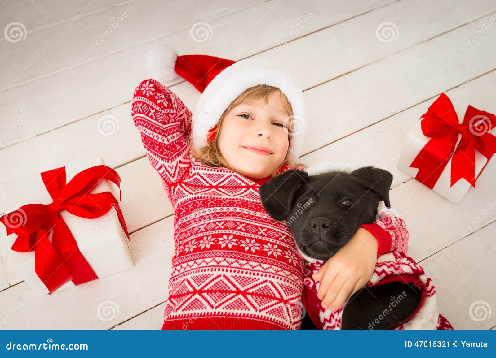 Bambino e cane nel Natale. Bambino e cane felici con il regalo di Natale Bambino vestito in cappello di Santa Claus Bambino divertendosi a casa Concetto di festa di natale