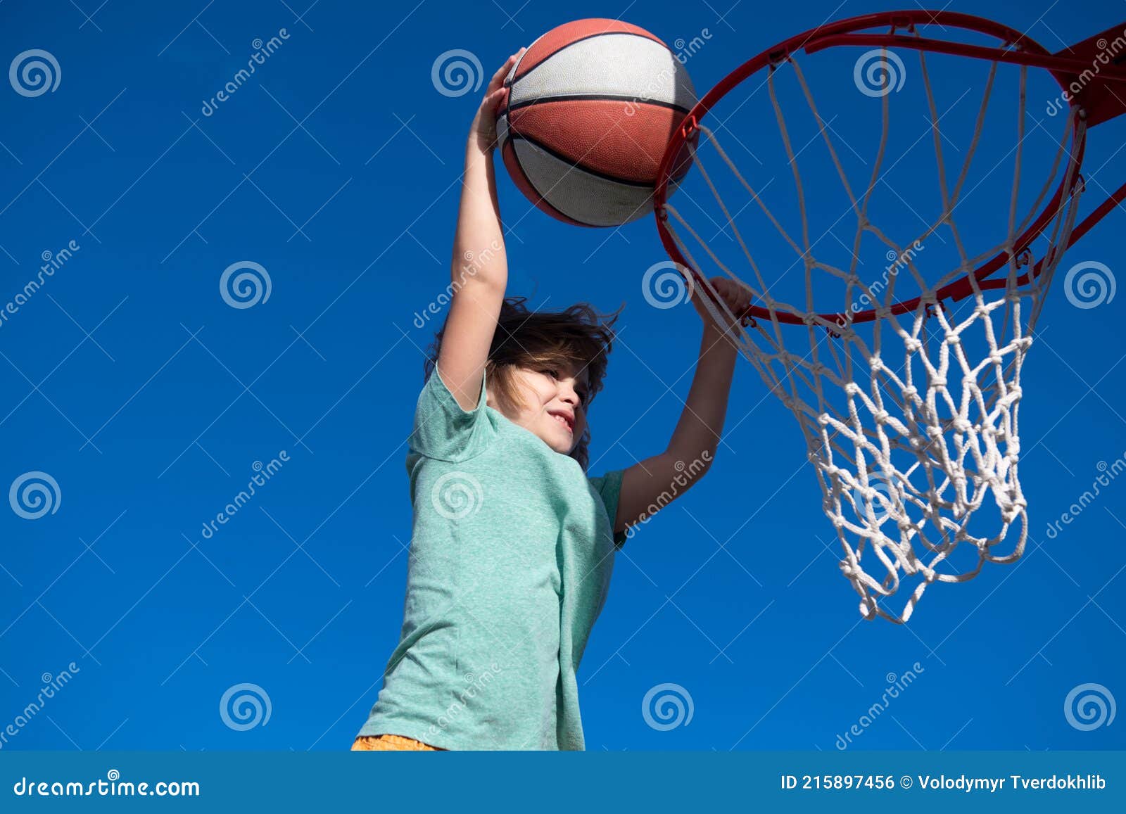 Giocatore di basket bambino che corre e schiaccia la palla bambino attivo  che si diverte a giocare all'aperto con il basket