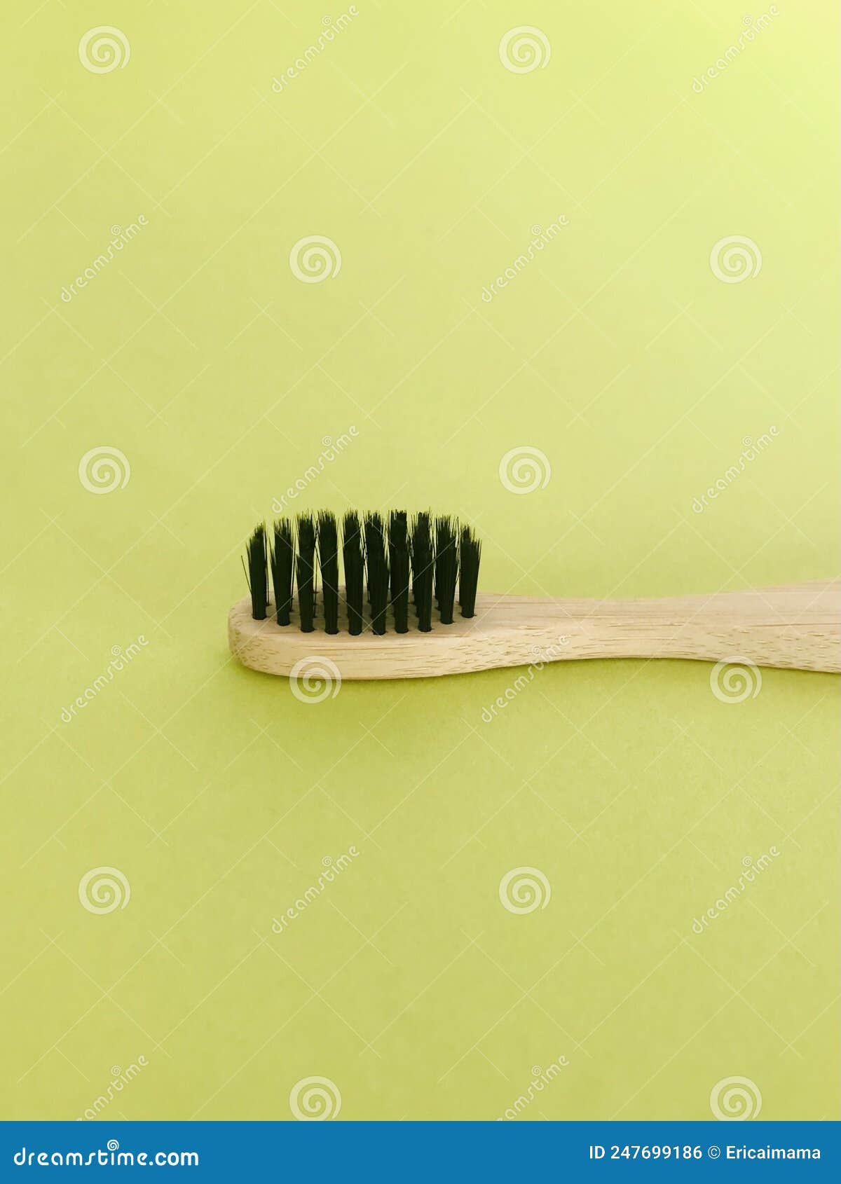 charcoal infused bamboo toothbrush on yellowish green background. vertical.