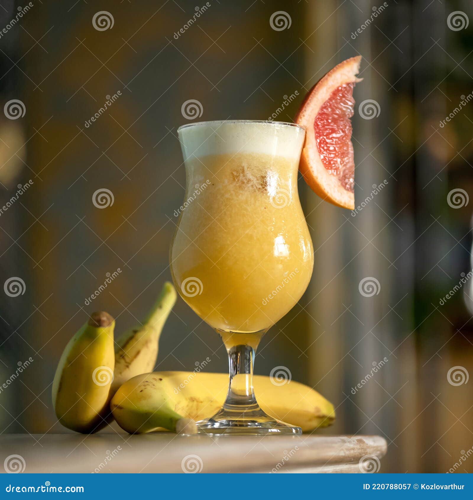 banana and citrus smoothie drink. goblet or glass with mixed shaked fruits on blurred background. refreshing detox