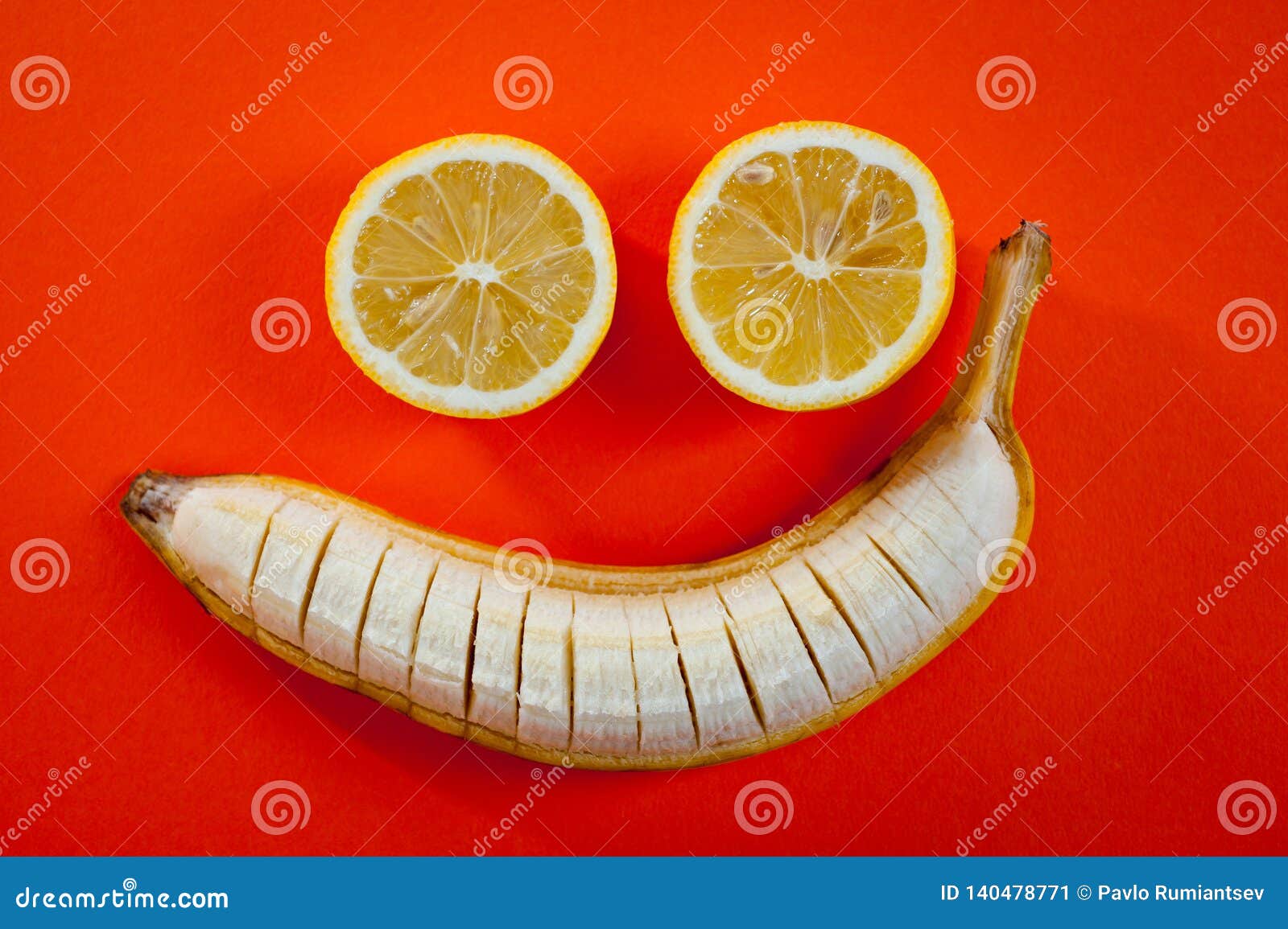 Banana and Two Lemons Lying in the Shape of a Smiley on a Bright Orange