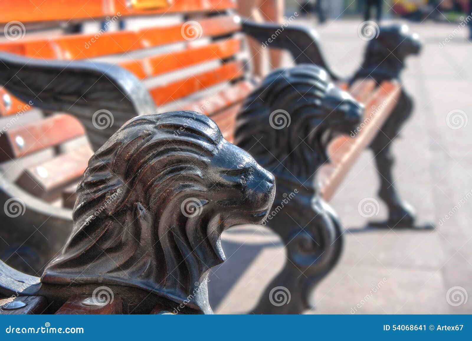 Un banc de parc avec des jambes de fonte sous forme de tête d'un lion