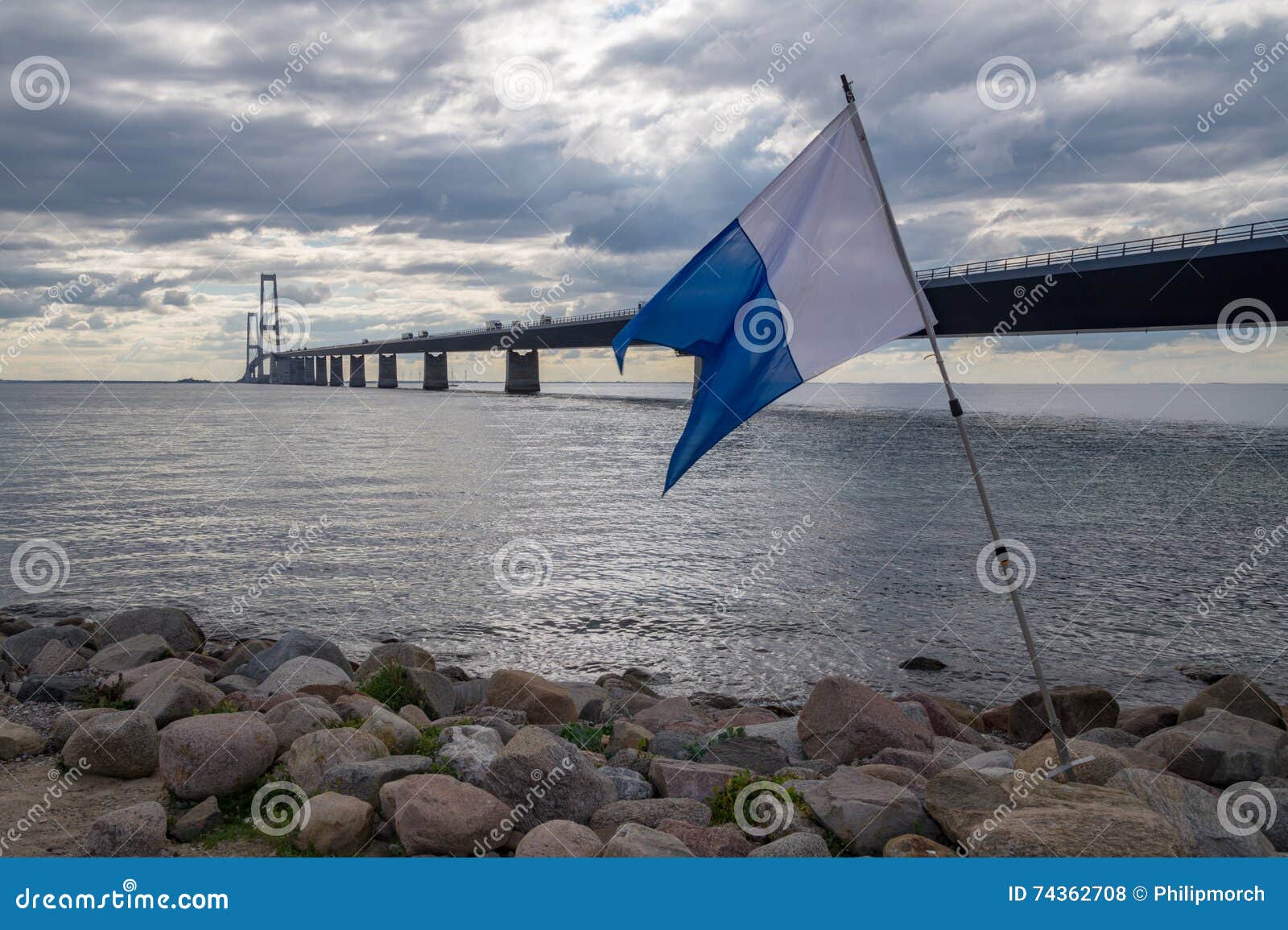 Bandeira do mergulho autônomo na frente da ponte. Bandeira na frente da grande ponte da correia, Dinamarca do mergulho autônomo, e sob um céu dramático