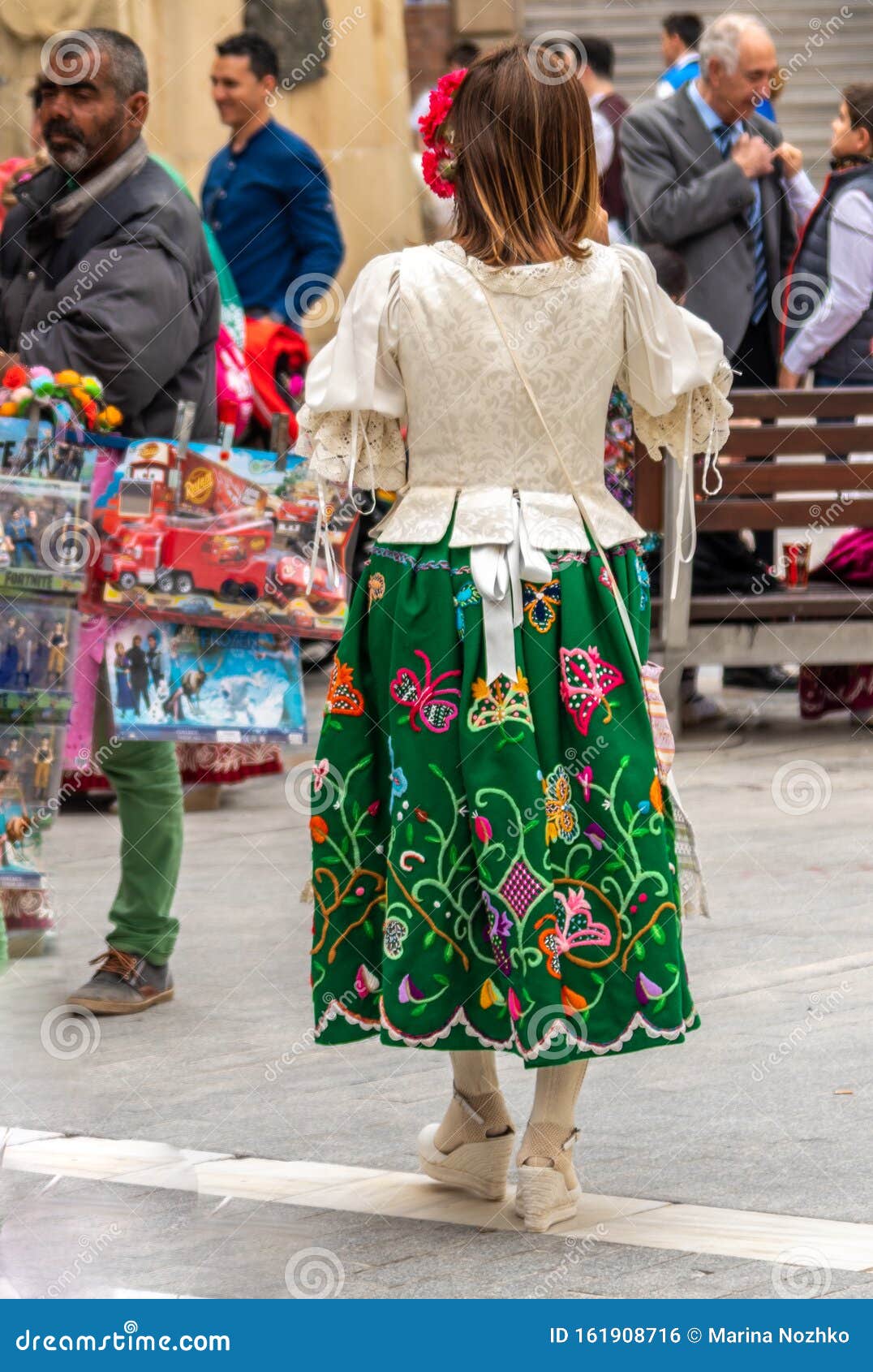 A Women in a Traditional Embroidered Skirt Walking in the Street during ...