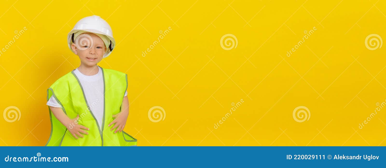 anner cute smiling boy on a yellow background in the uniform of a builder.