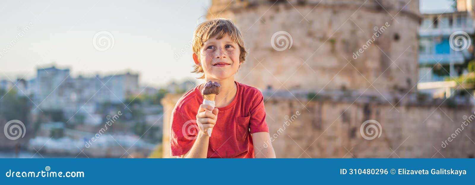 banner, long format boy tourist eating turkish ice cream on background of hidirlik tower in antalya against the backdrop