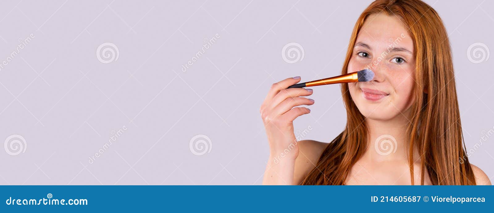 banner, long format, grey background. redhead woman, smiling looking at camera applying makeup to her nose with cosmetic