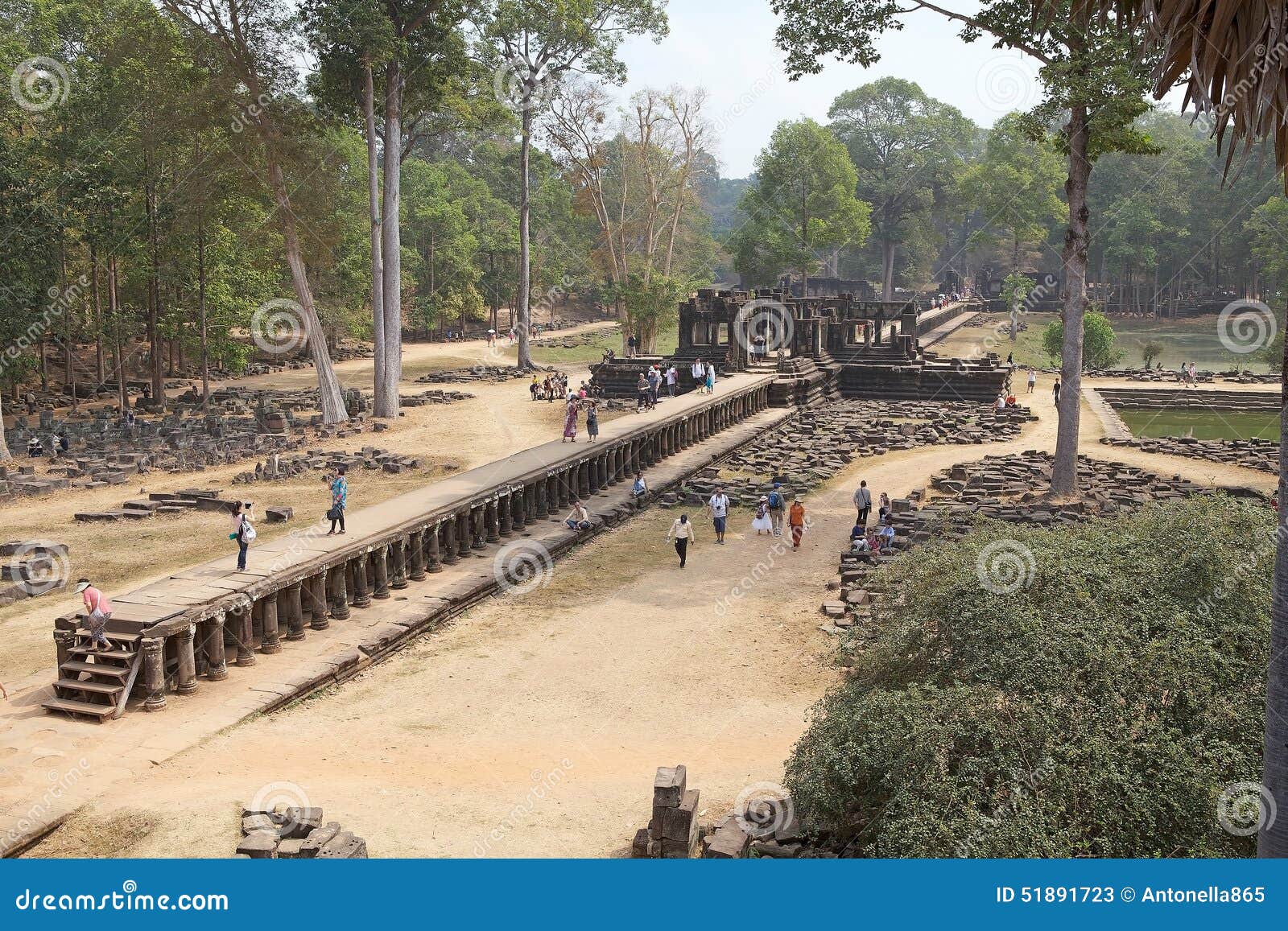 Los turistas están caminando a lo largo del terraplén de la piedra arenisca al templo de Baphuon, situado en Angkor Thom, al noroeste de Bayon, Angkor, Siem Reap, Camboya El terraplén tiene cerca de 200 m de largo Cerca de dos tercios de la manera a lo largo del causaway un pavillion cruciforme gravemente arruinado entrecruza el camino