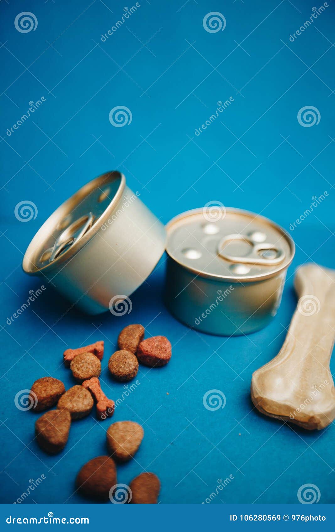 Barattoli di latta con alimento per animali domestici. Pasto nutriente per il vostro piccolo compagno Barattoli di latta di alimento per animali domestici e di un osso di masticazione su un fondo luminoso del blu di un-colore Cura di animale domestico e concetto veterinario Spase per il vostro testo o immagine