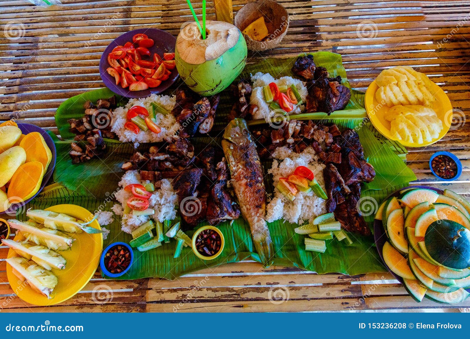 barbecue of chicken, pork and fish is served on bamboo leaves with vegetables and fruits. filipino cuisine