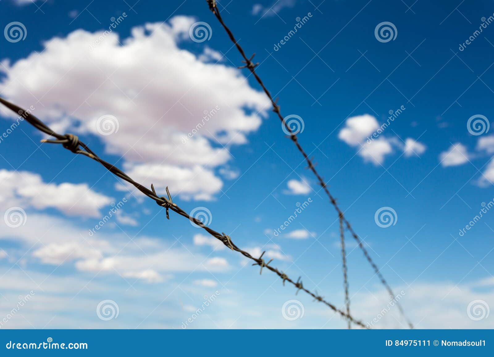 barbed wire againdt blue cloudy sky.