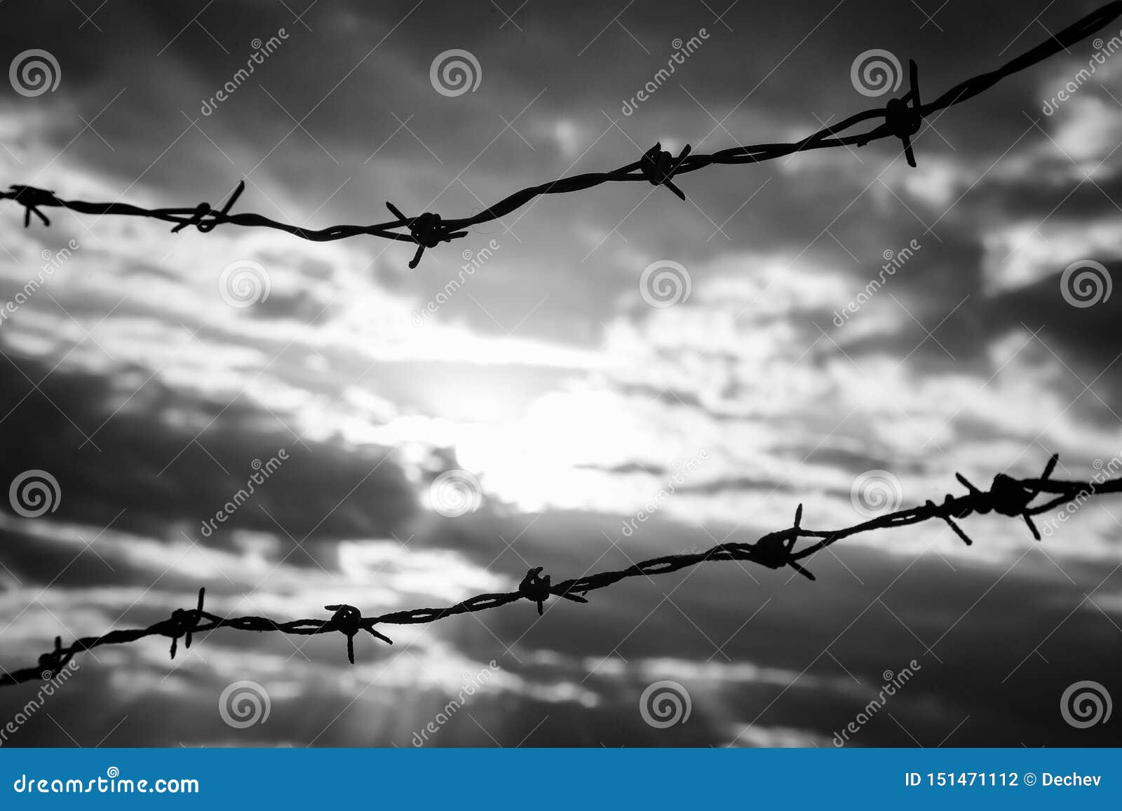 Clôture En Fil De Fer Barbelé Contre Un Ciel Sombre Et Dramatique.