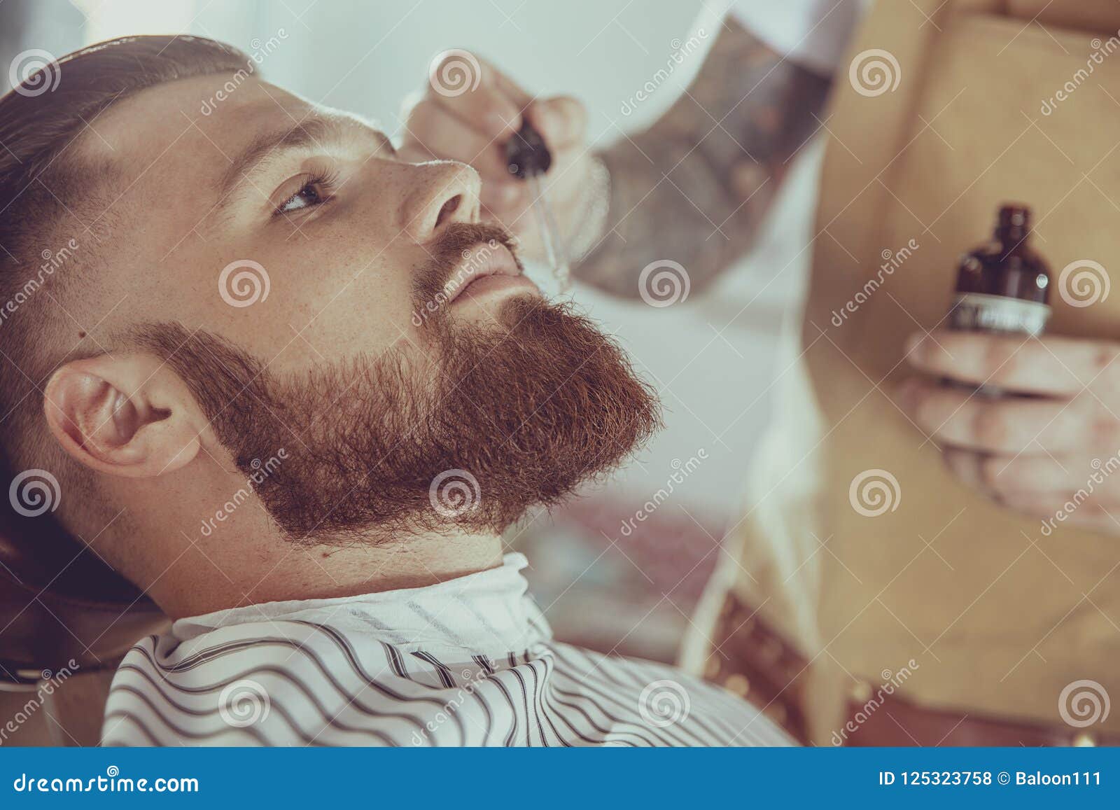 the barber applies the beard oil with a dropper