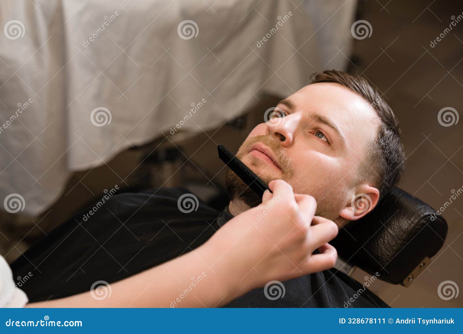 barber combs beard with comb while shaving caucasian man