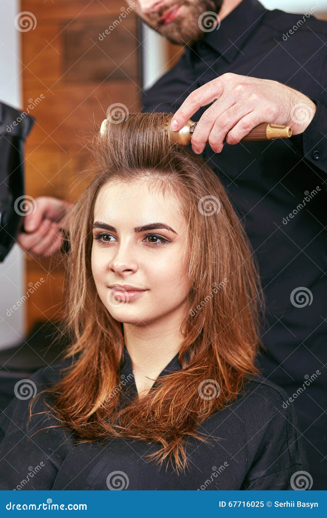 barber dries the hair with the hair dryer of young, beautiful girl in a beauty salon