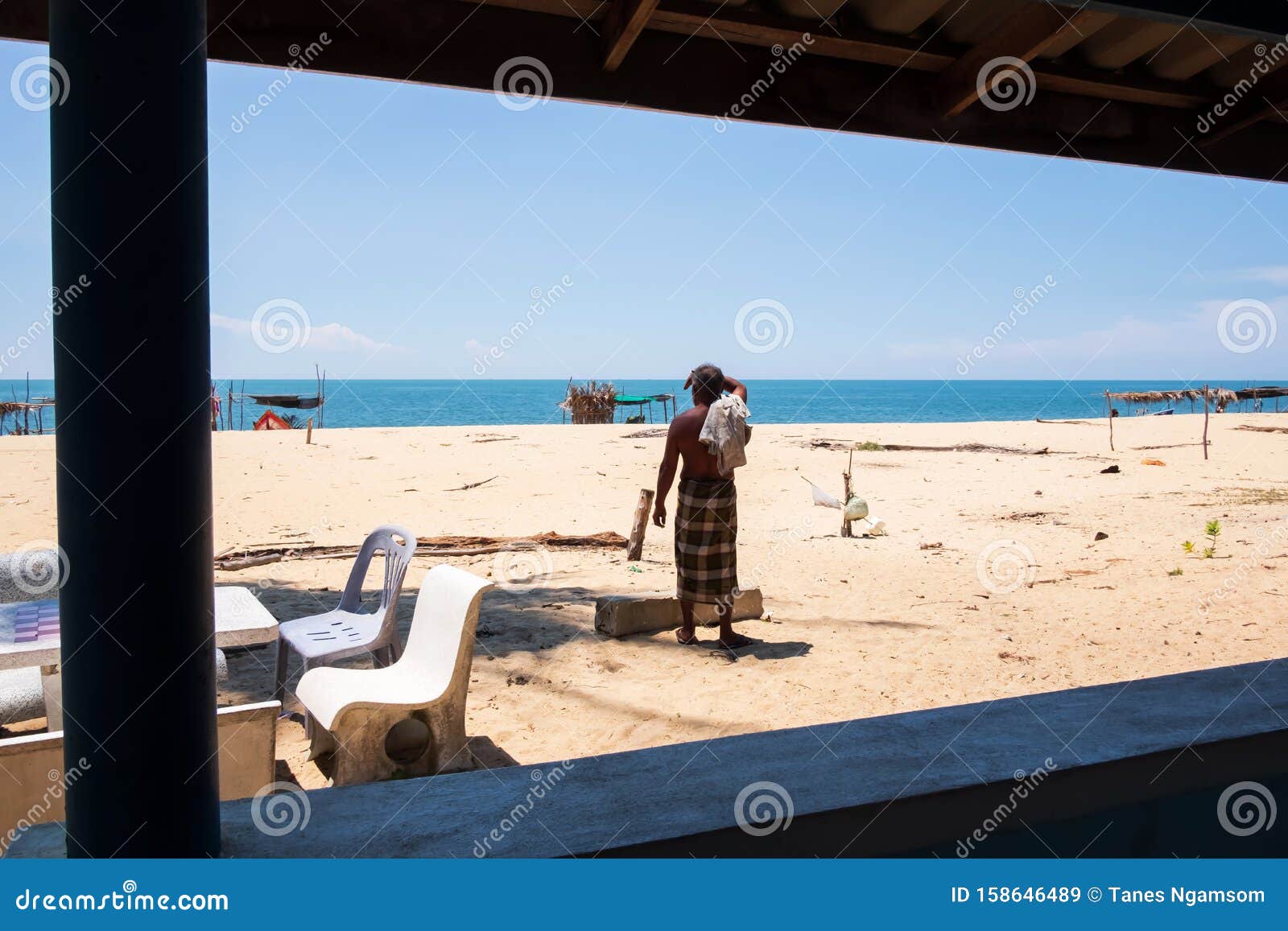 Bare-chested Asian Senior Fisherman Stands on the Beach Editorial