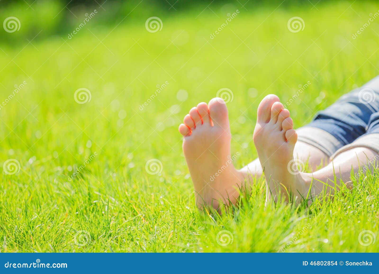 bare feet on green grass with autumn leaves