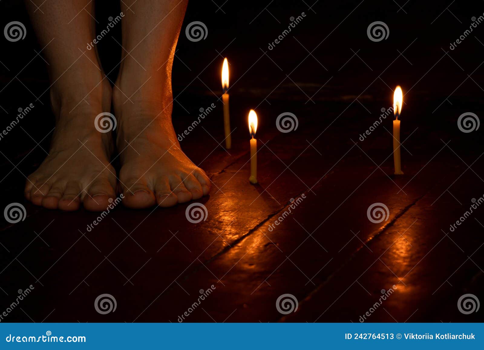 bare female feet on the floor at home in the dark near candles, female feet