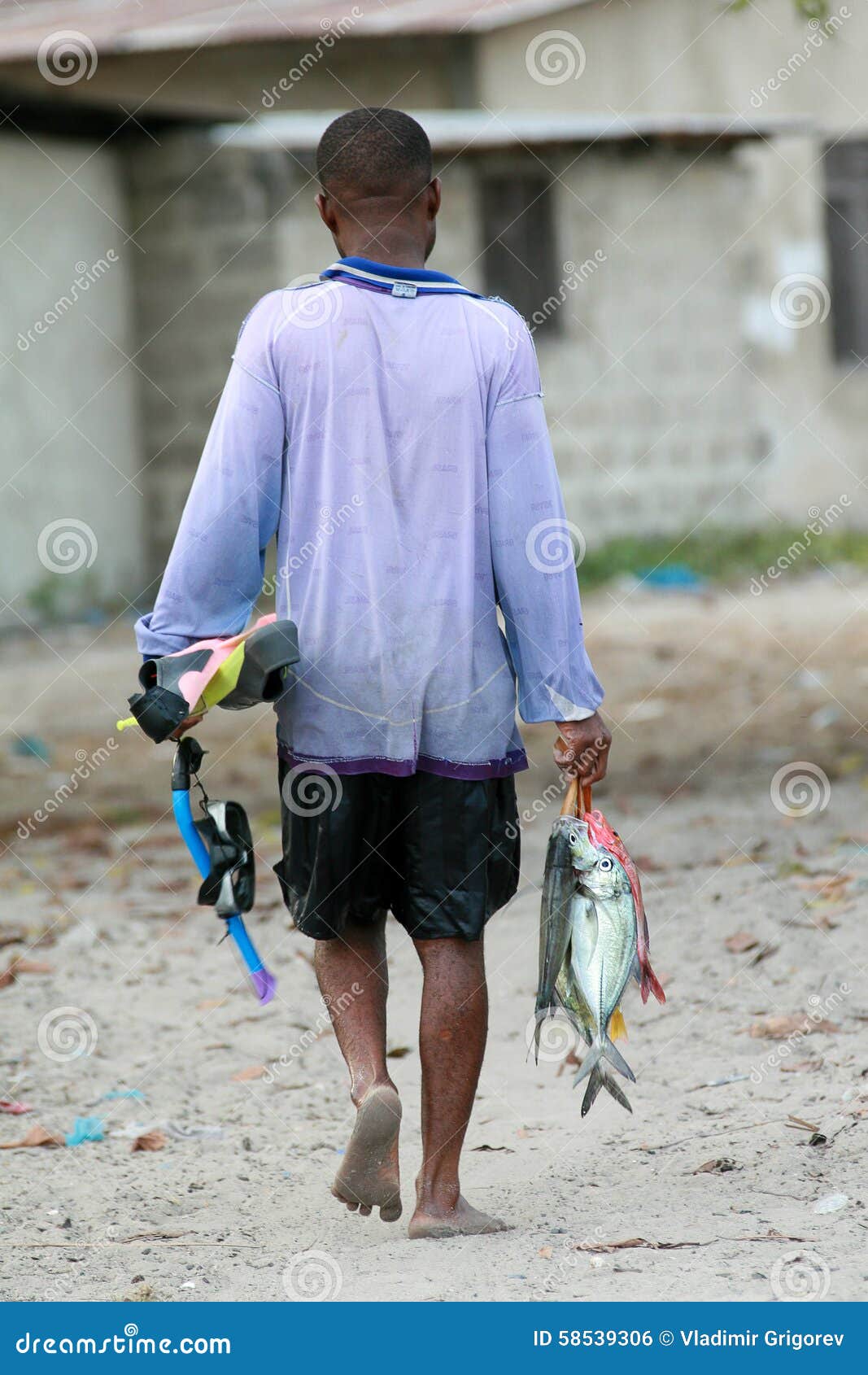 Barefoot African Black Fisherman Diver Carries a Caught Fish