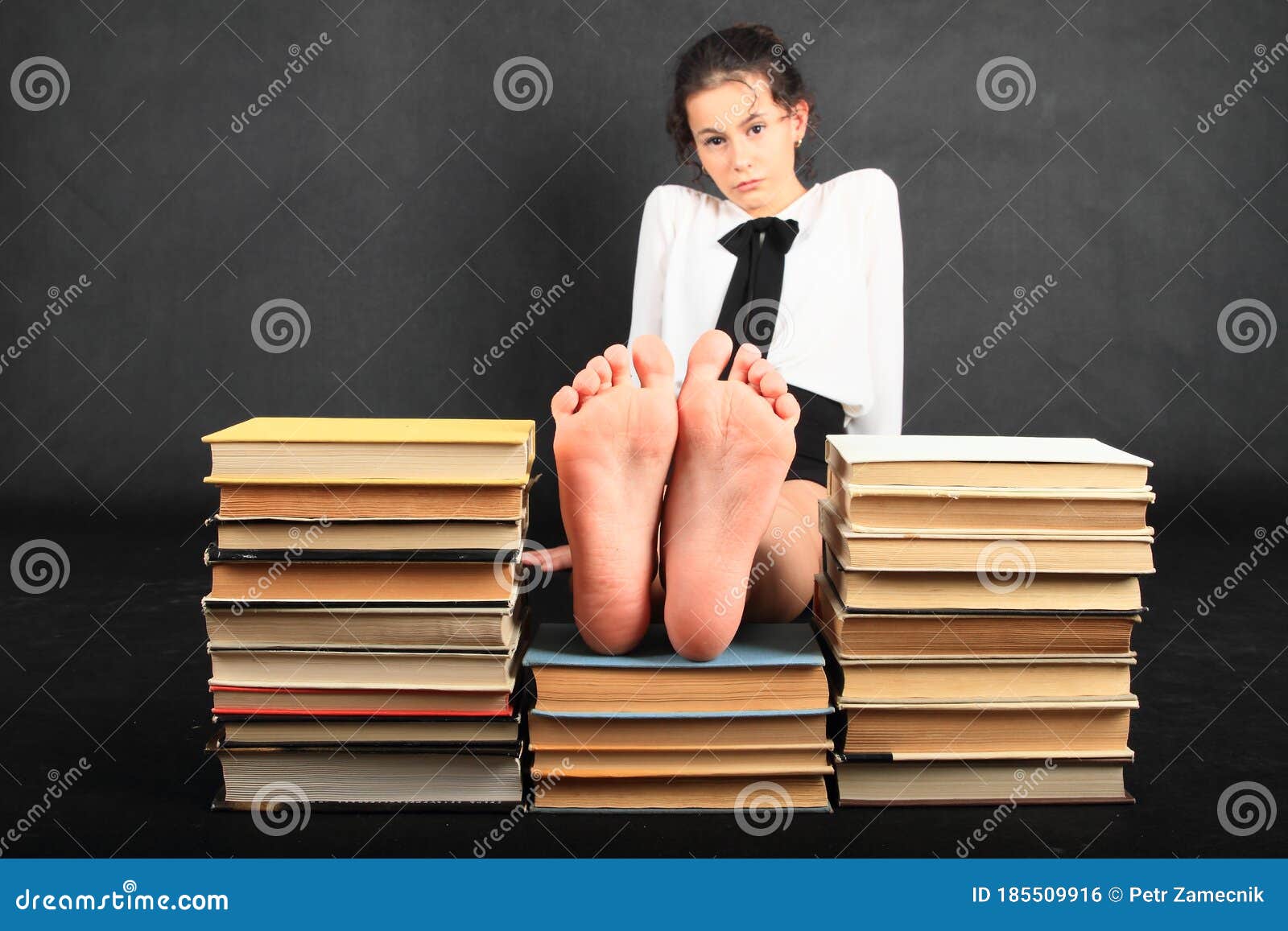 soles of bare feet of teenage girl on top of old books