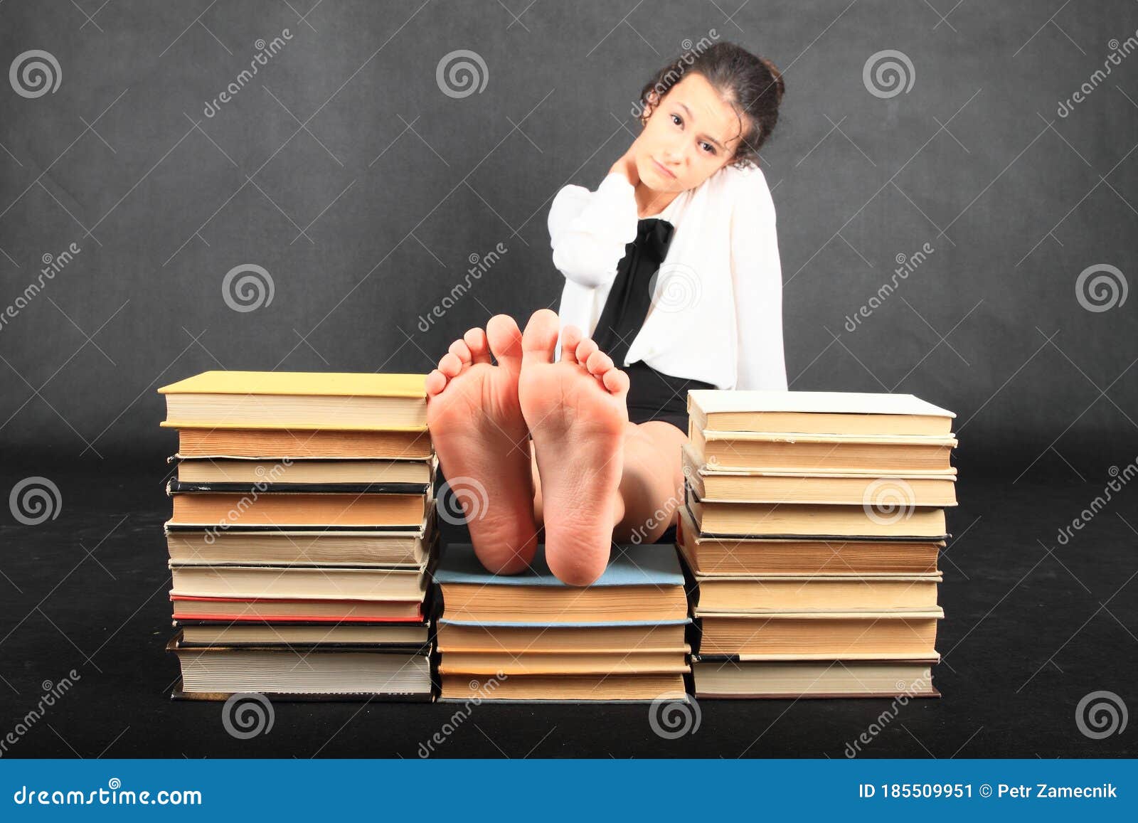 soles of bare feet of teenage girl on top of old books