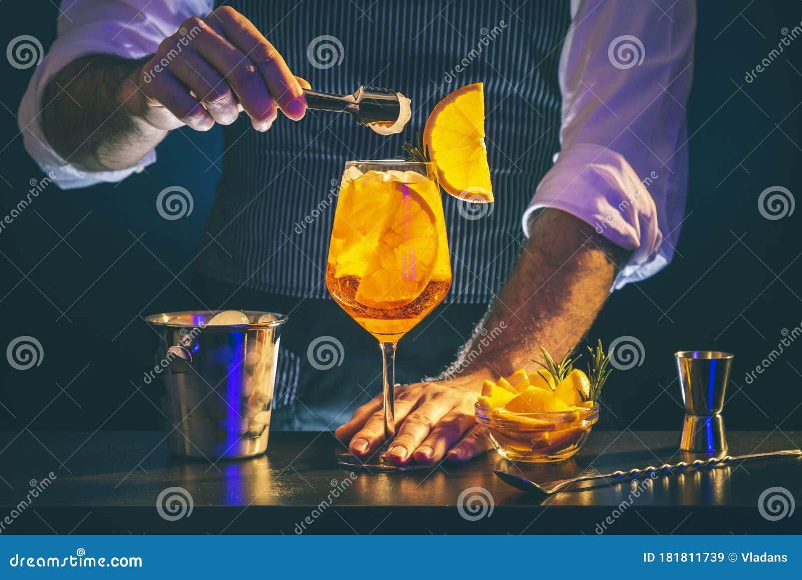 Il barista aggiunge il ghiaccio nel bicchiere da cocktail con la
