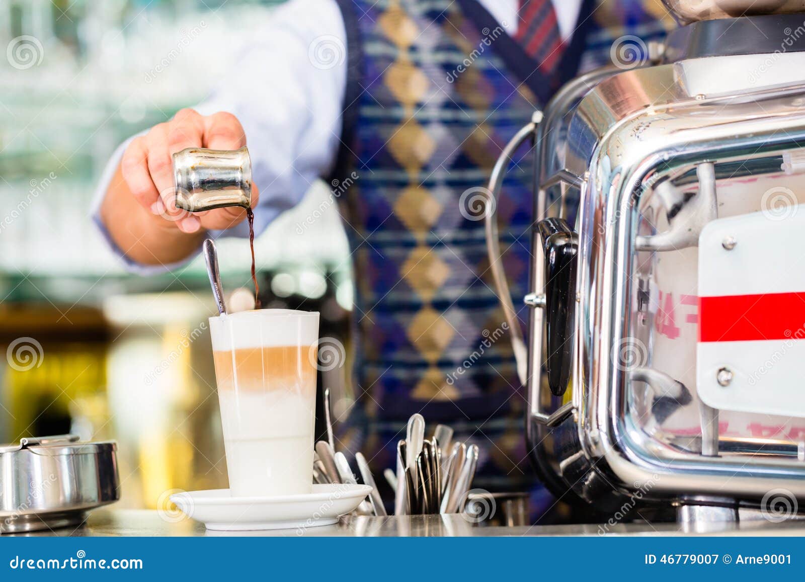 Barista in auslaufendem Espresso des Cafés schoss in Latte macchiato. Barista im Café oder in Café, die auslaufenden Espresso zubereiten, schoss im Glas Latte macchiato