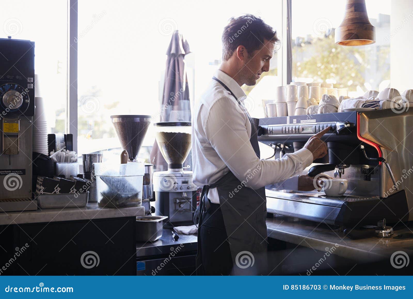 barista making coffee in delicatessen using machine