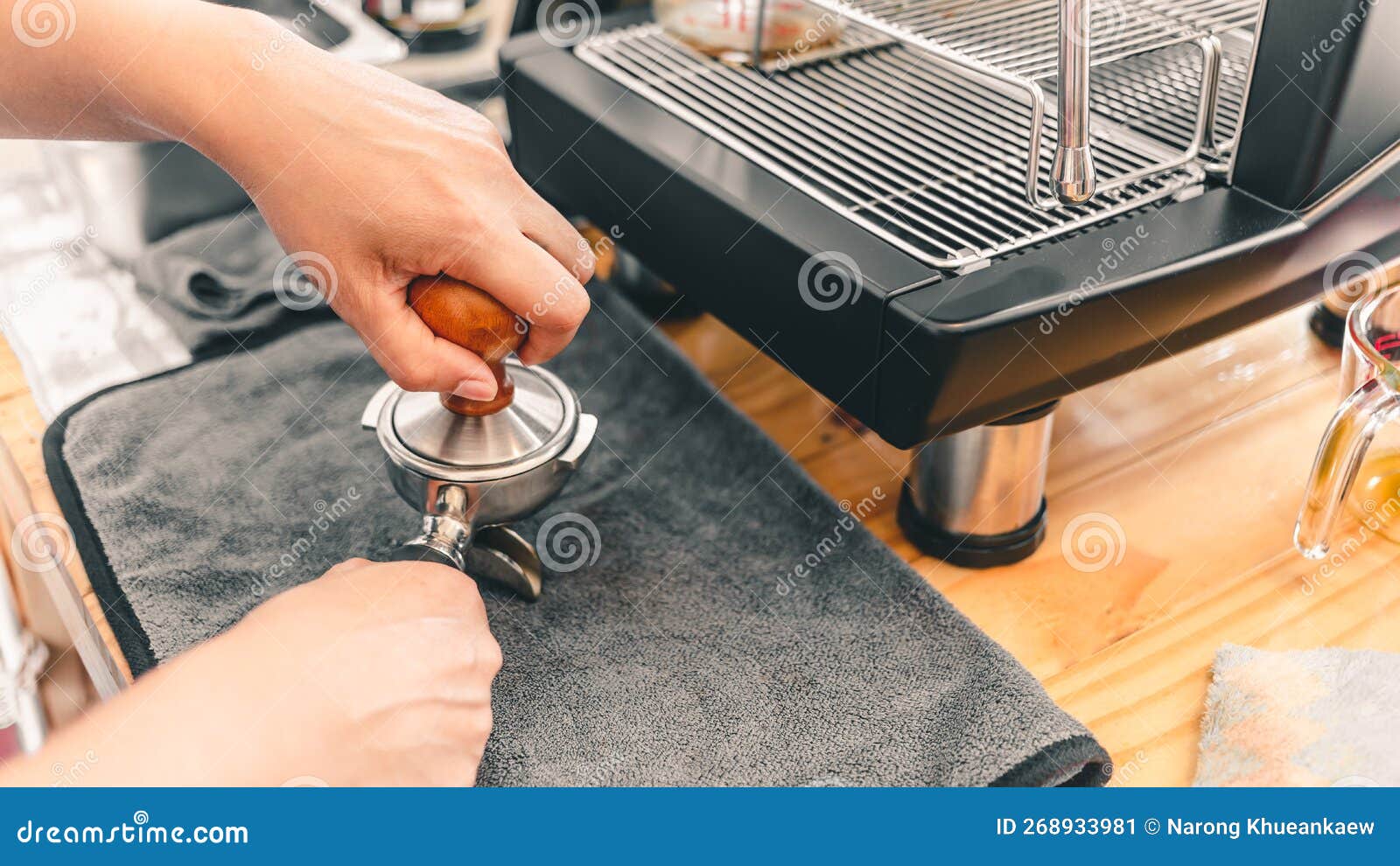 The Barista Presses Ground Coffee Using a Tamper on a Wooden Counter
