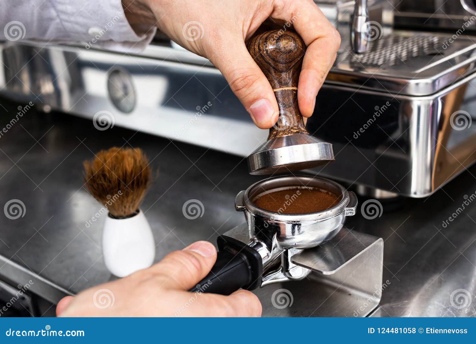 barista pressing ground coffee into portafilter with a tamper.