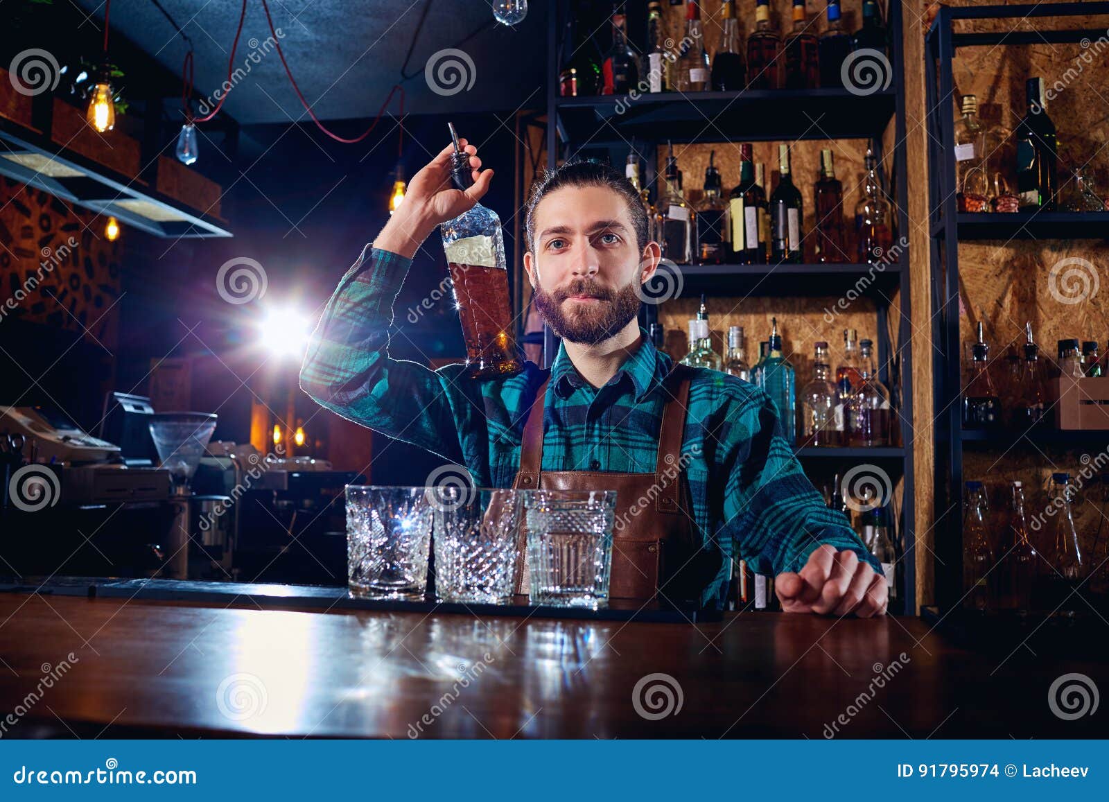 Barman Bartender with a Bottle of Alcohol Behind the Counter in Stock
