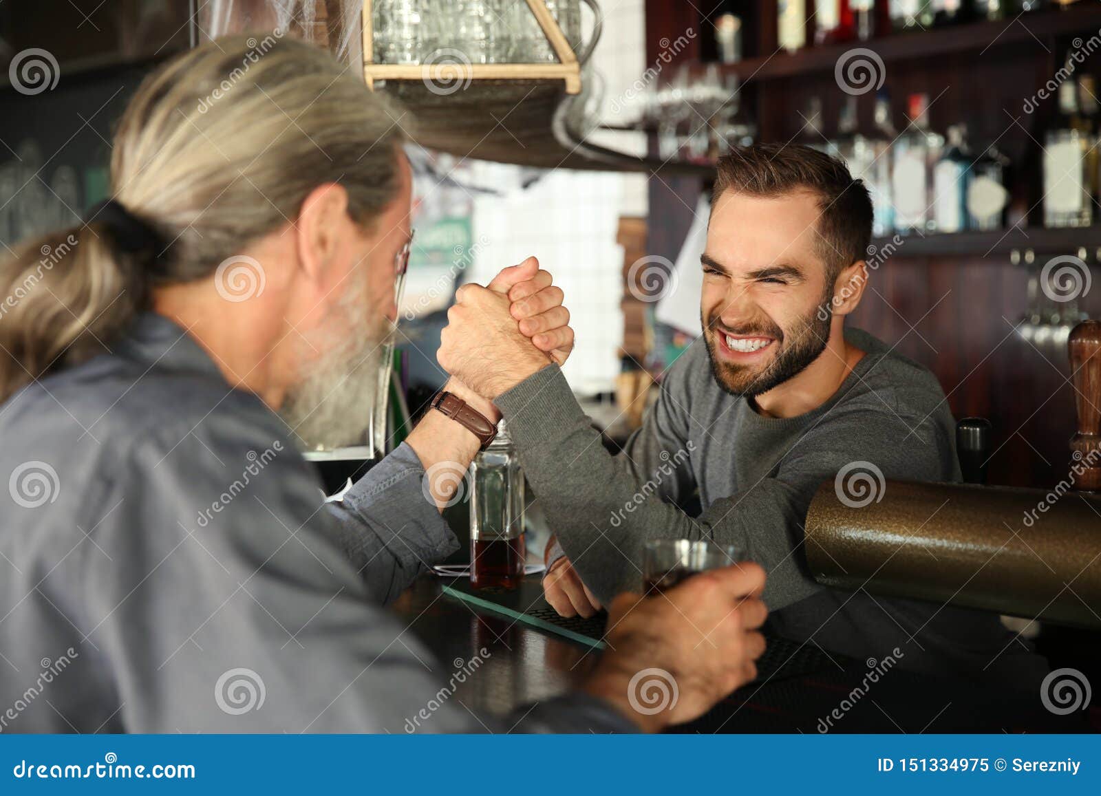 Barman and Client Having Armwrestling Competition in Pub Stock Image
