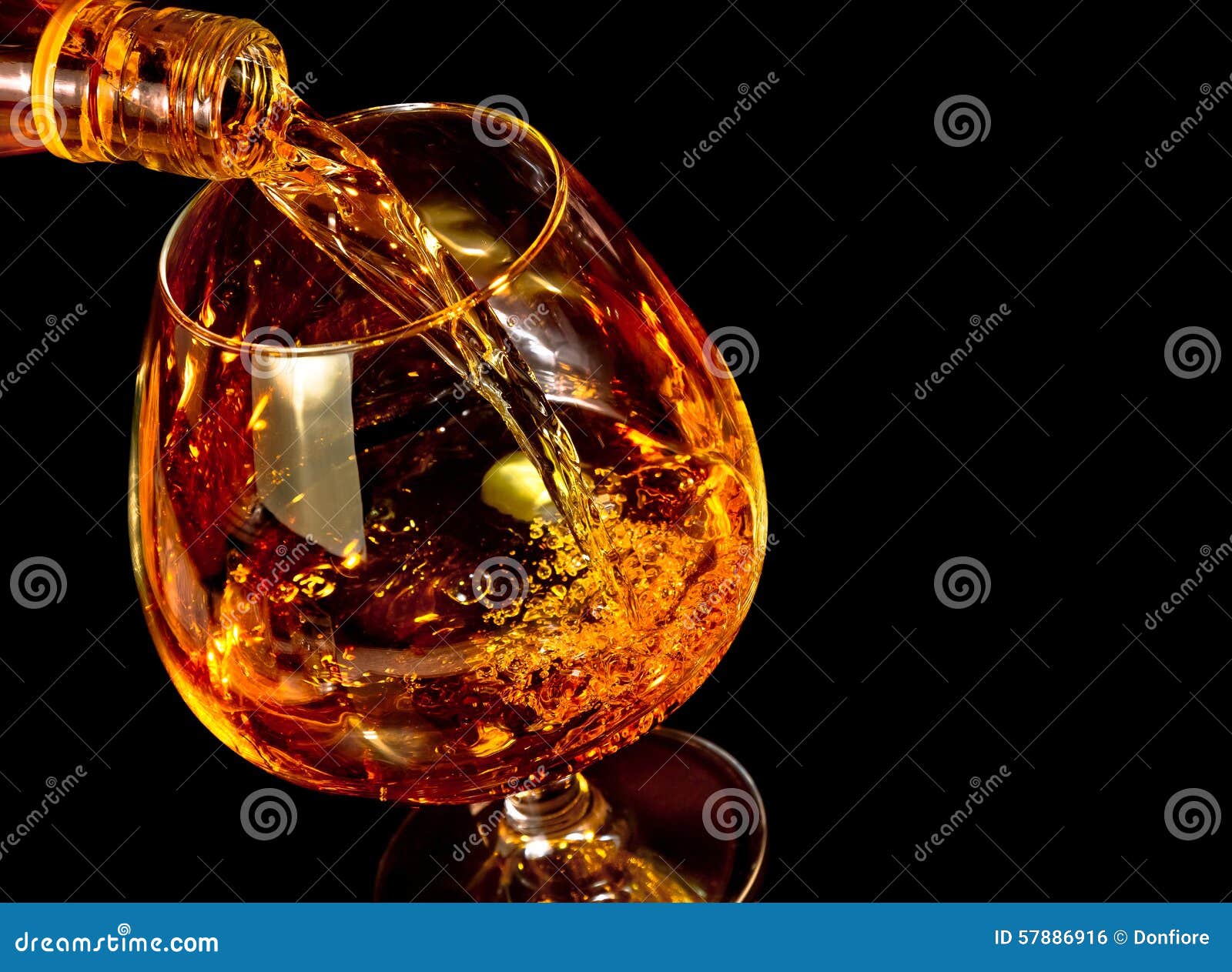 barman pouring snifter of brandy in elegant typical cognac glass on black background
