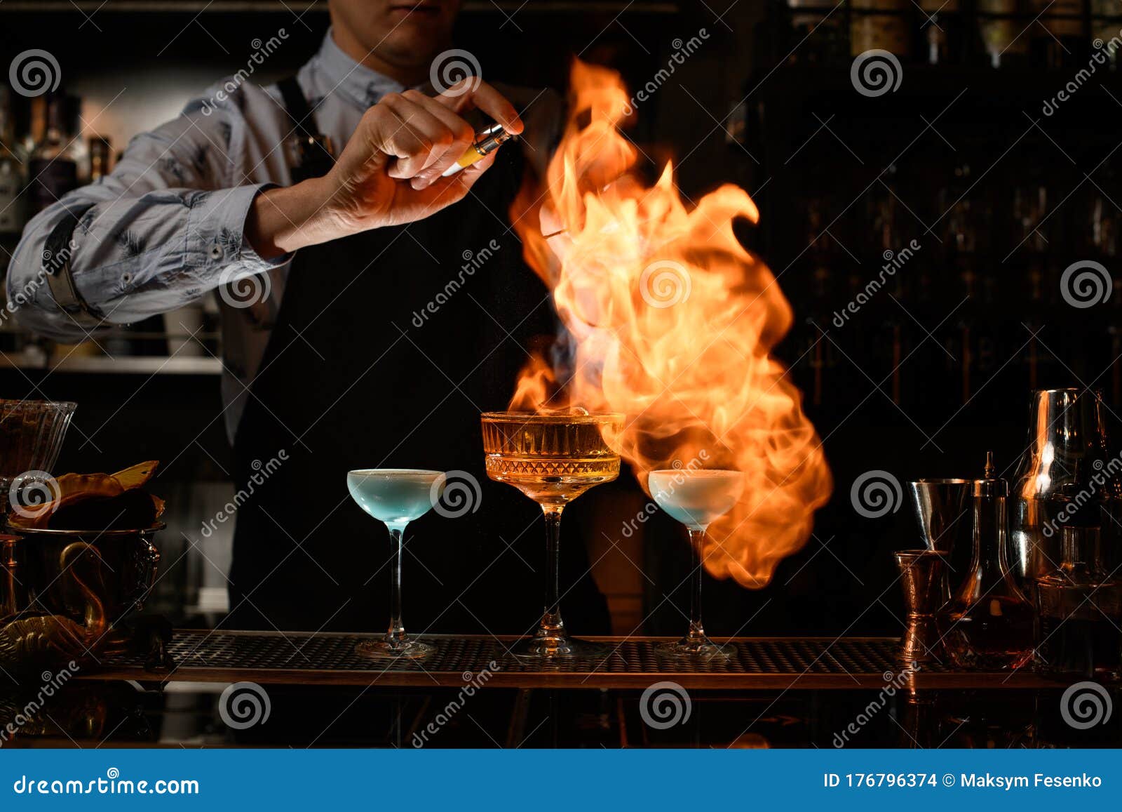 Bartender Makes Fire Over Several Glasses with Cocktails Stock Photo