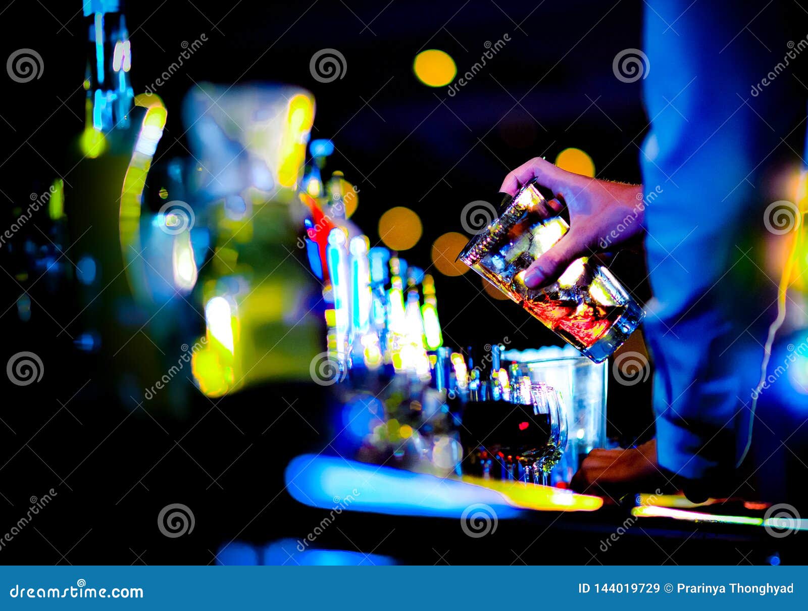 bartender making alcohol cocktail at bar counter at nightclub, barman is making cocktail