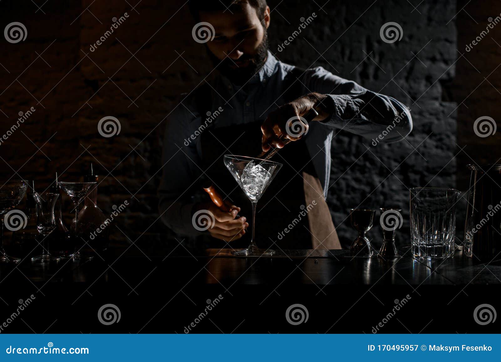 bartender putting an ice cube with twezzers to the martini glass
