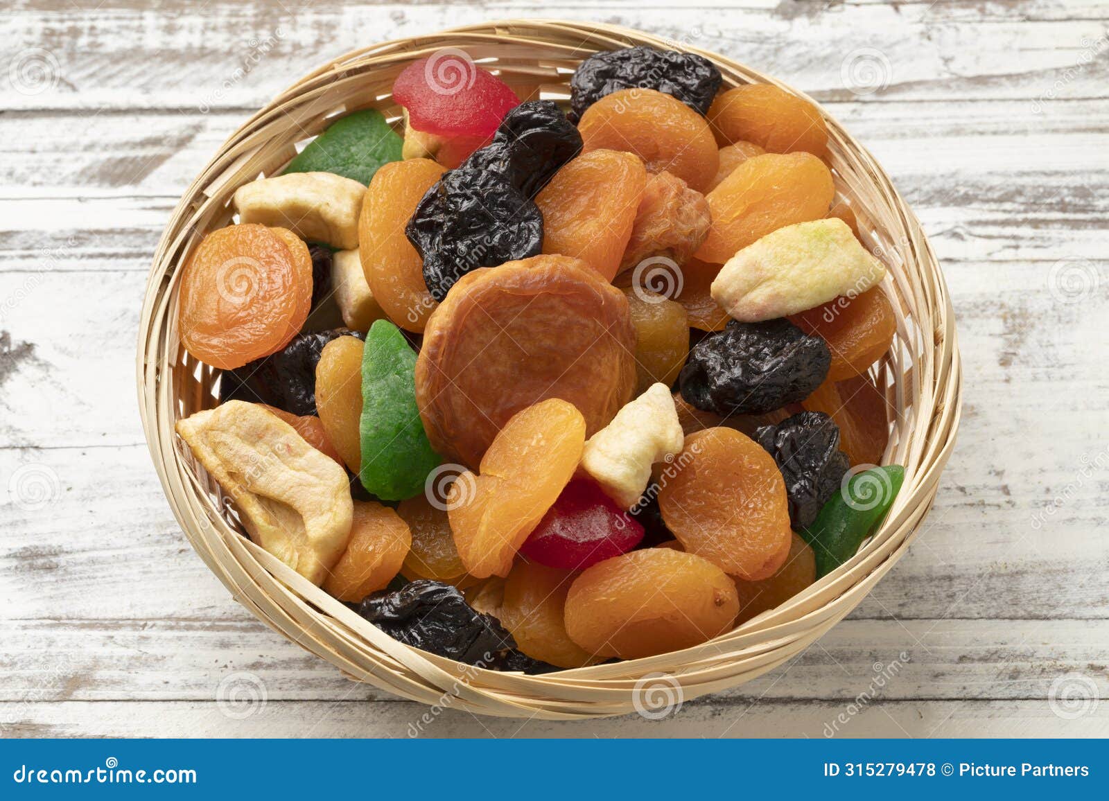 basket with dried fruit, tutti frutti, on wooden background