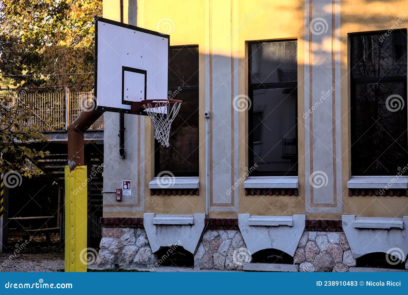 Basketball Hoop in the Backyard of a School at Sunset Stock Image