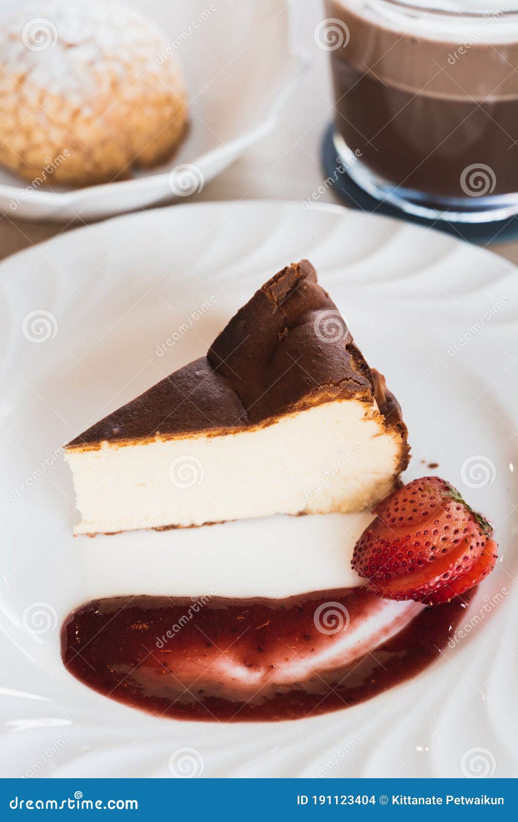 Basque Cheesecake with Strawberry Sauce on a Table with Hot Chocolate
