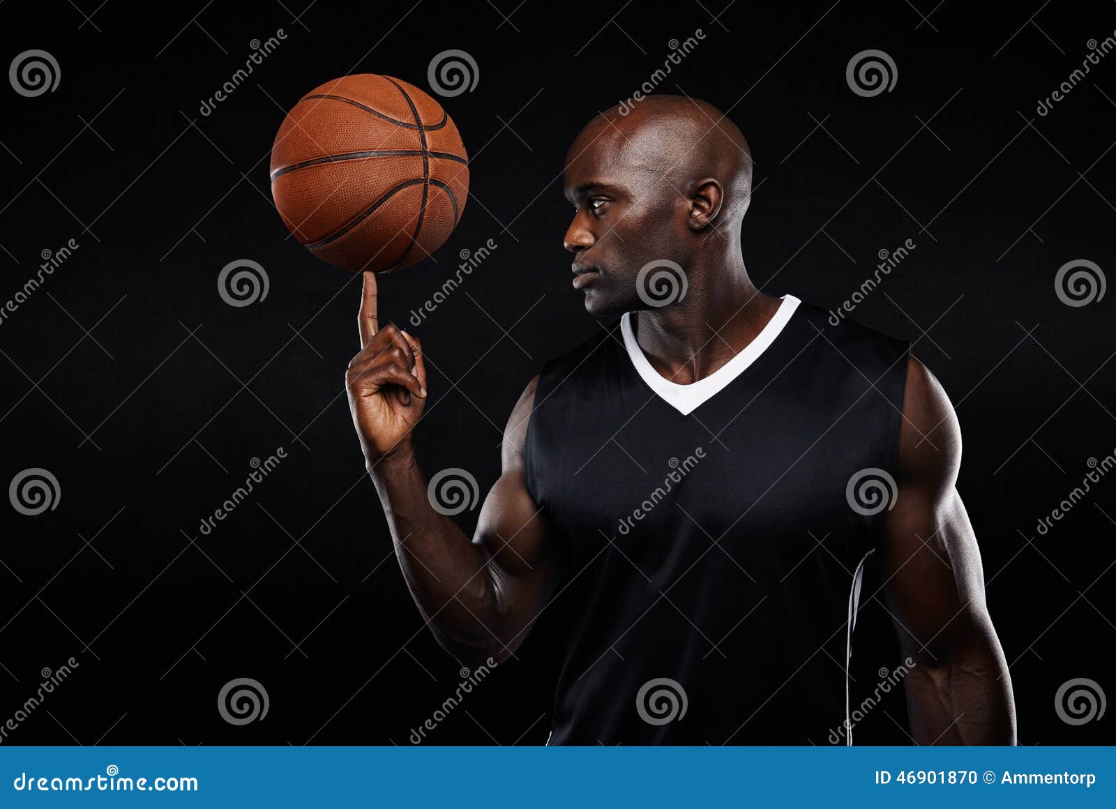 Retrato do basquetebol de equilíbrio do atleta africano novo em seu dedo contra o fundo preto Jogador de basquetebol focalizado