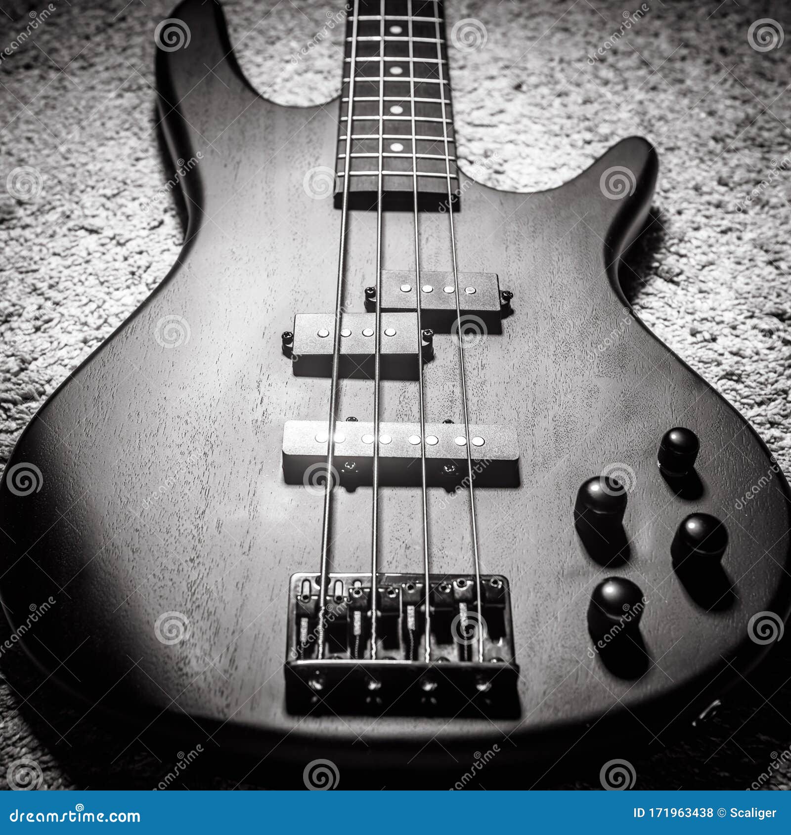 bass electric guitar with four strings in black and white. popular rock musical instrument. top view of bass guitar, focus on