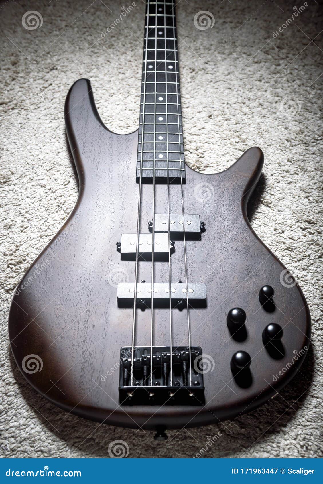 bass electric guitar with four strings. popular rock musical instrument. top view of brown bass on carpet