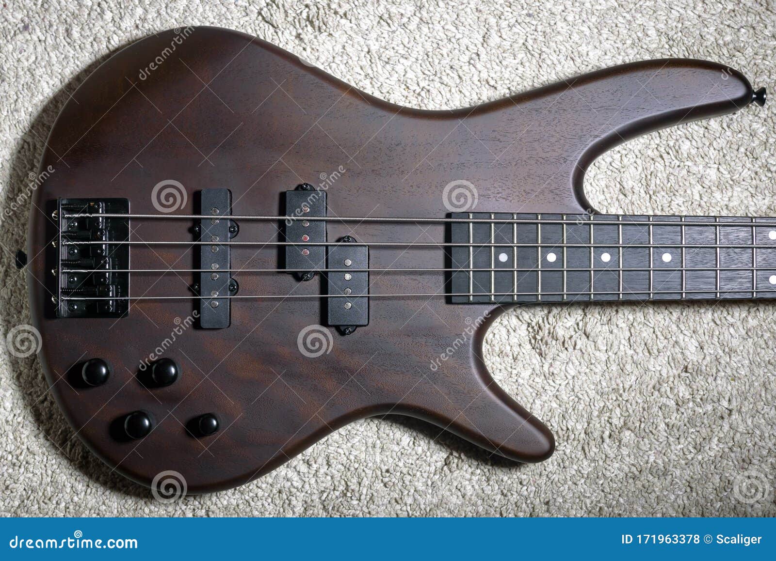 bass guitar with four strings. popular rock musical instrument. top view of brown electric bass on carpet